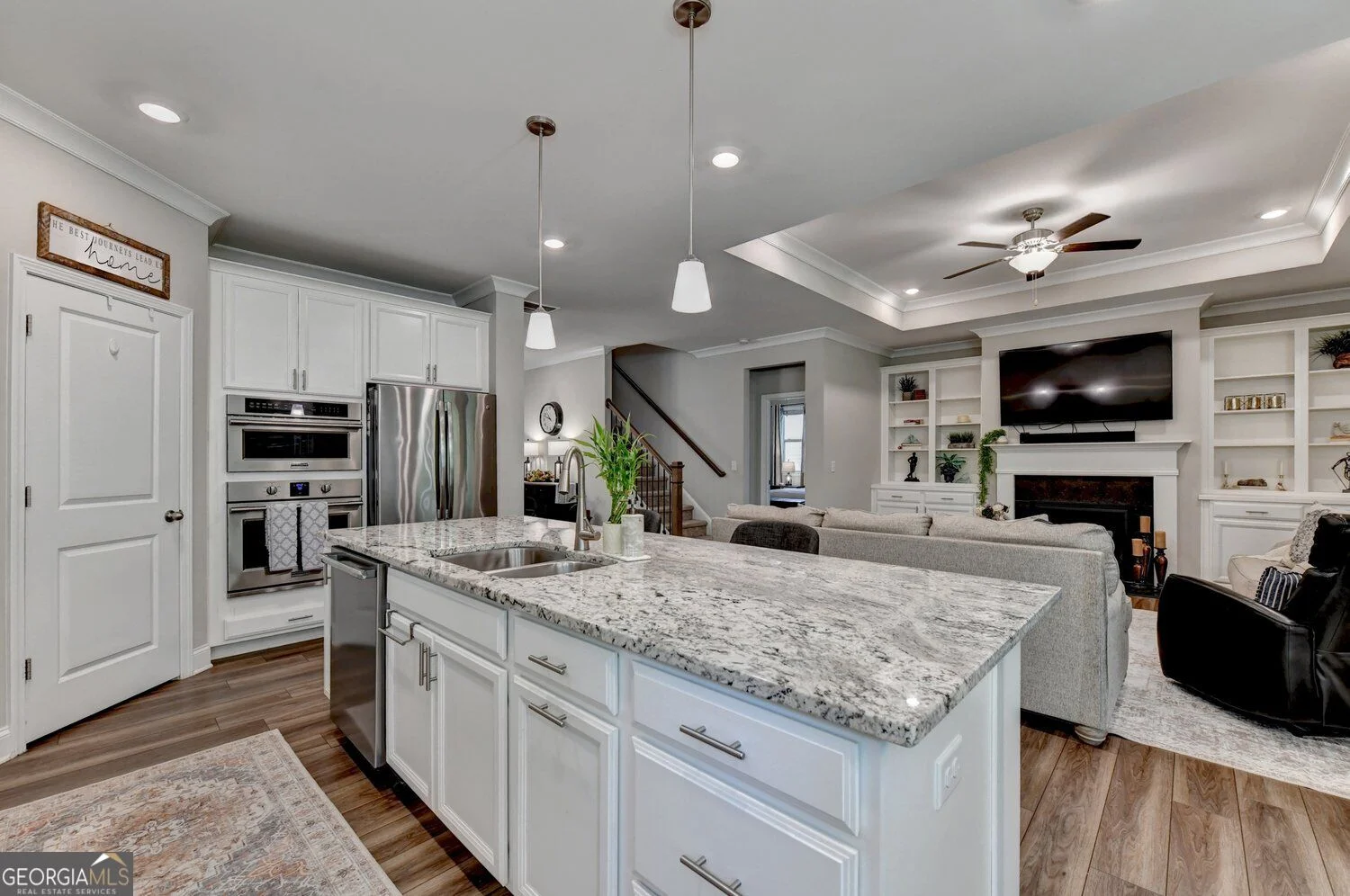 Kitchen with white cabinetry, stone-look countertops and an island facing the family room