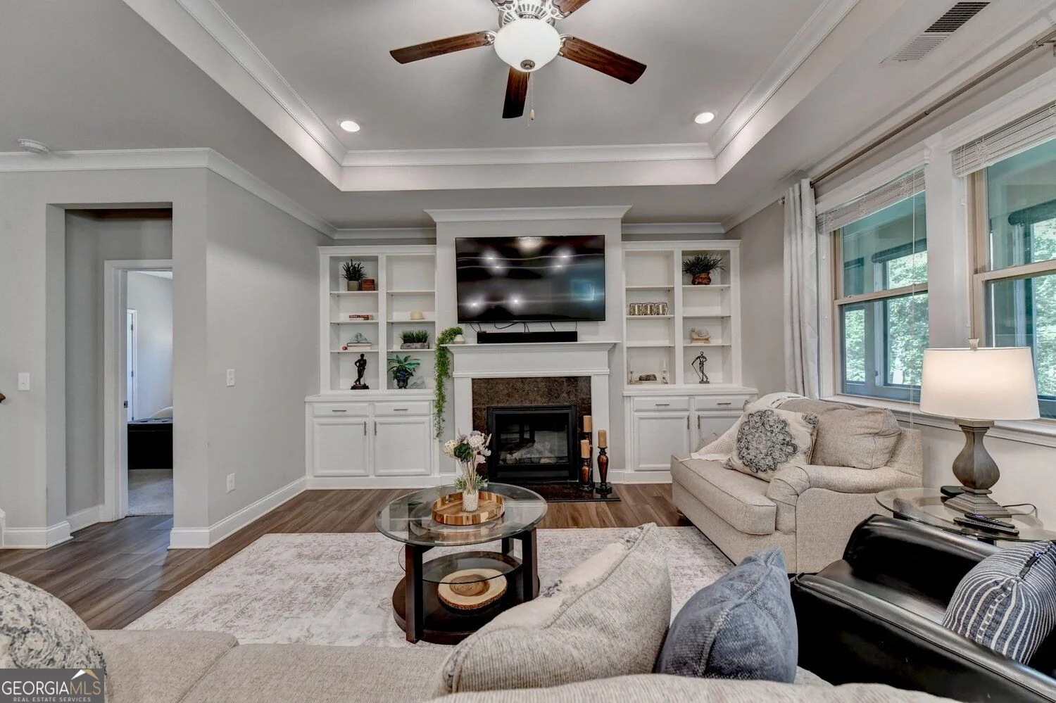 Family room with fireplace, built-in shelving, large windows and tray ceiling